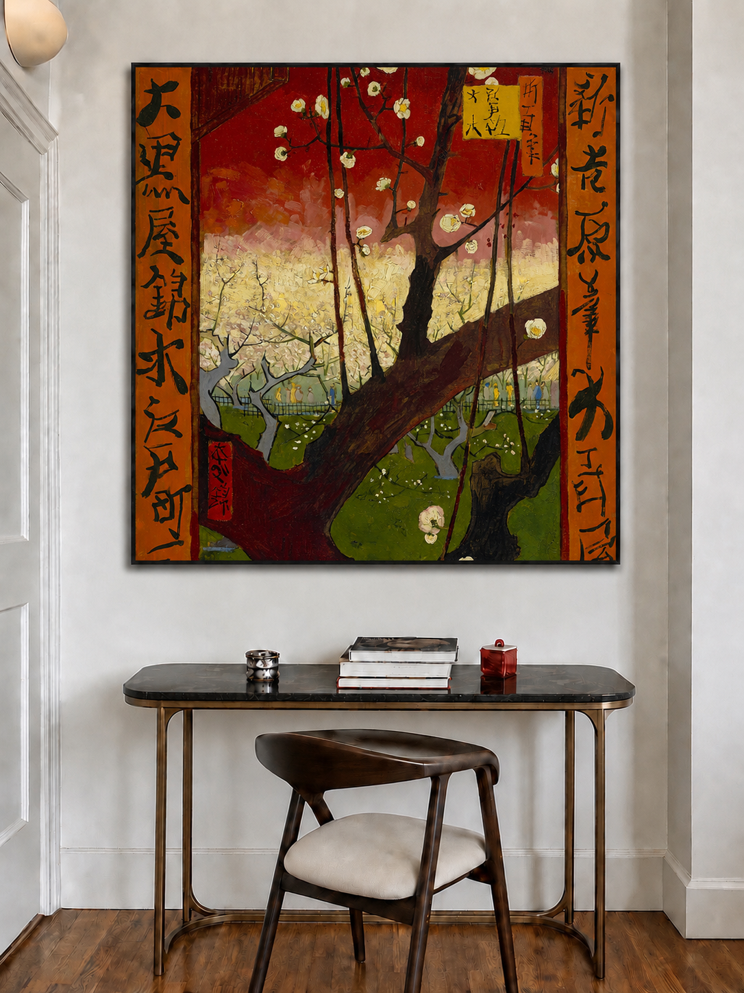 A framed Japanese-style wall art print featuring a cherry blossom tree with red, gold, green, and brown tones, displayed above a dark console table and chair in a modern interior setting.